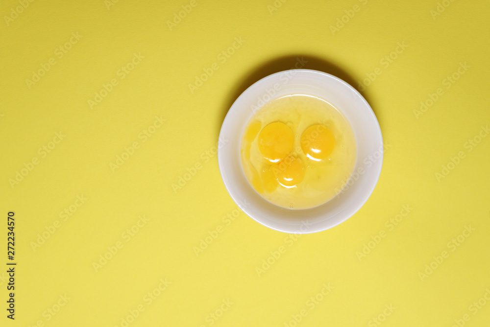 three broken chicken eggs in a plate. fresh raw protein food. yellow background. three broken chicken eggs in a plate. fresh raw protein food. yellow background.