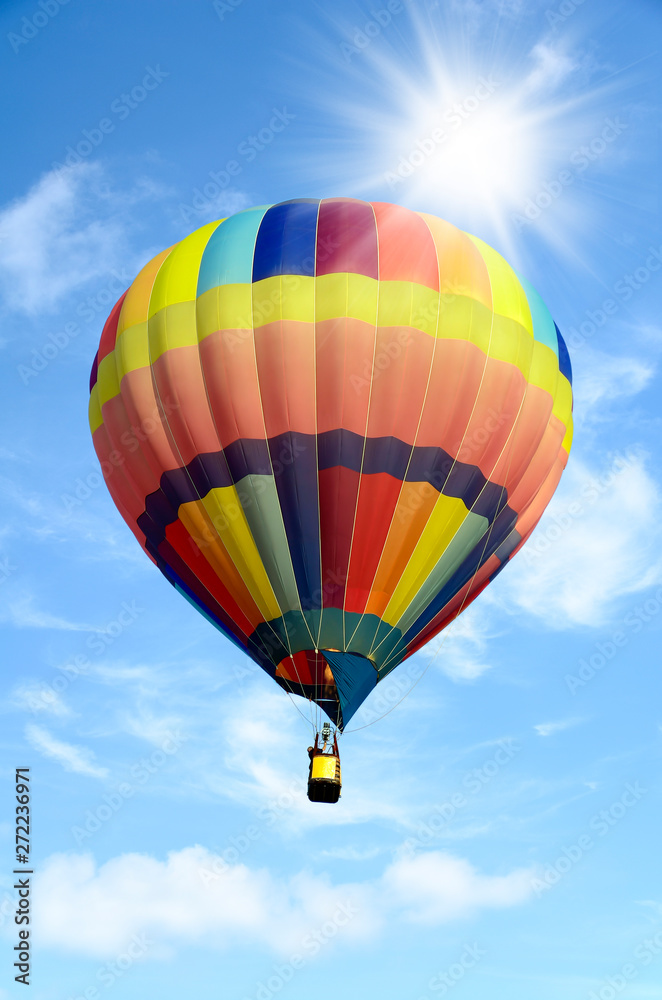 Naklejka premium Colorful hot air balloon over bright sky with clouds.