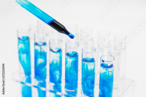 In the laboratory, scientists synthesized and analyzed the compound by dropping colored liquid in test tubes. White background close-up.