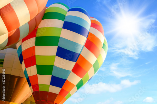 Colorful hot air balloon over bright sky with clouds.