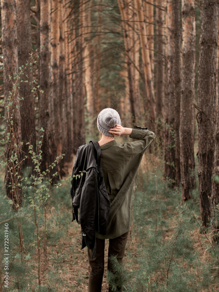 Stylish young woman posing in nature in street style clothing.