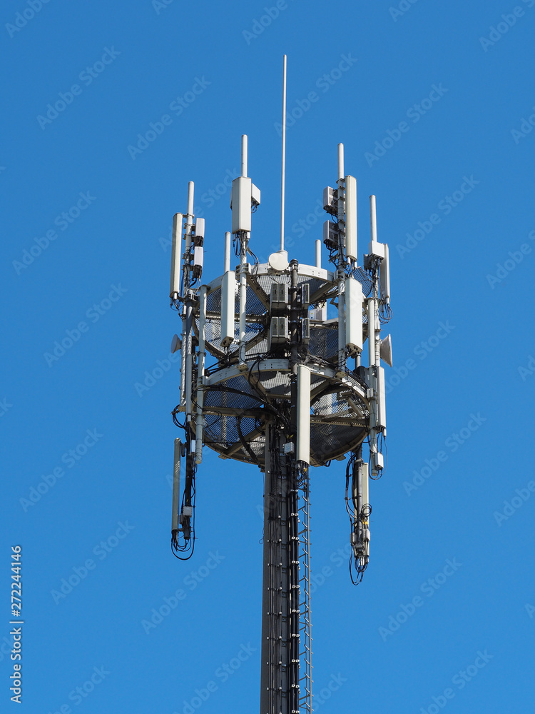 A tower with telecommunications antennas on a background of blue sky A tower with telecommunications antennas on a background of blue sky