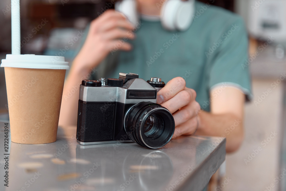 Male with retro camera and hot drink indoors