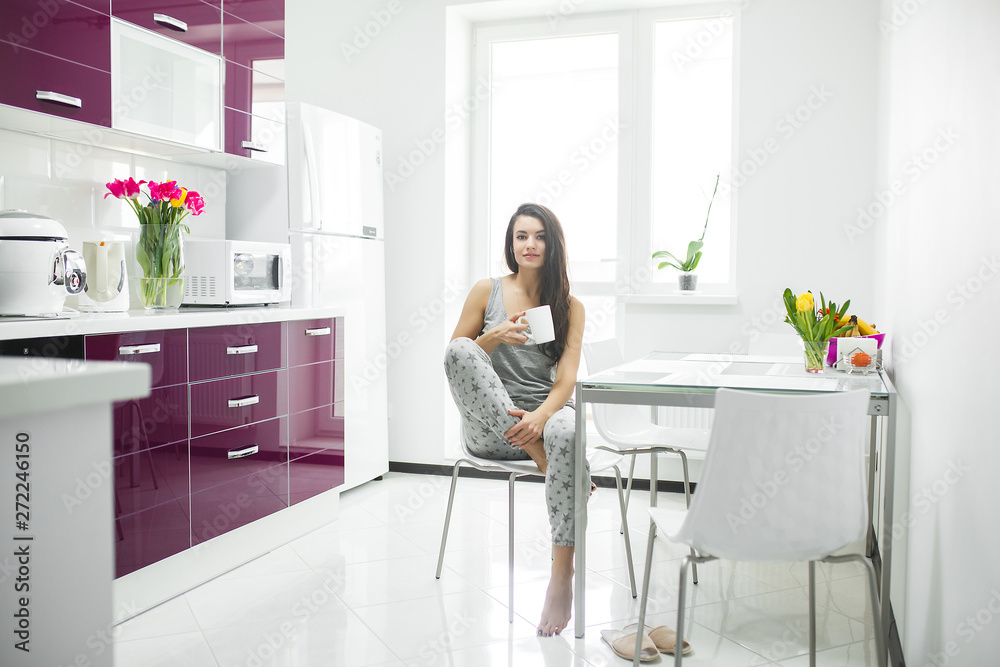 Young beautiful woman in the early morning having coffee on the kitchen. Fresh morning. Bracing drink. Fees for work. Awake lady. Young beautiful woman in the early morning having coffee on the kitchen. Fresh morning. Bracing drink. Fees for work. Awake lady.