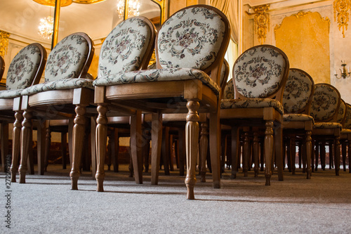 a group of vintage wooden chairs stands in several rows in a large old room with a luxurious interior. empty auditorium in the assembly hall. hall for performances without spectators photo