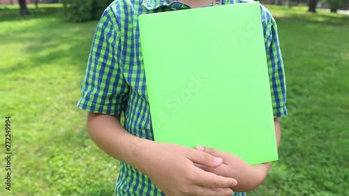 Closeup view of big green paper book in hands of little 10 years old kid. Real time full hd video footage.