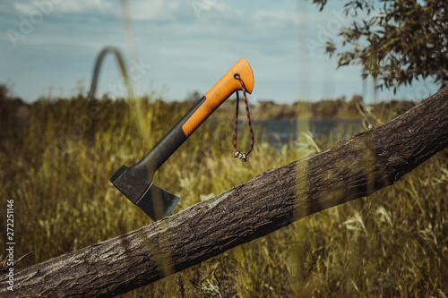 Foto Tourist or camping hatchet stuck in a wooden log after chopping, tourist or hiki