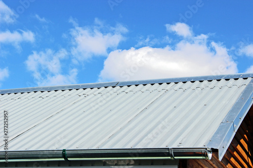 The new roof of a small country house against a blue sky with clouds. Construction and repair.