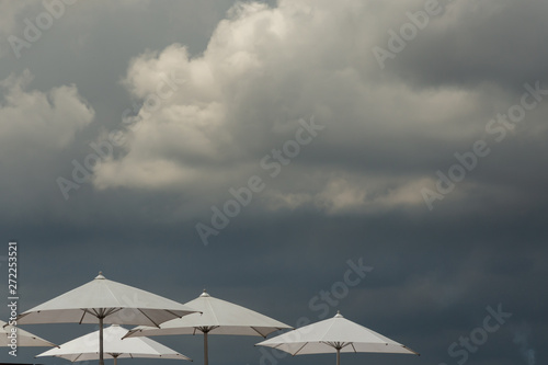white umbrellas against a threatening sky