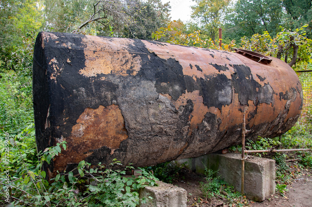 Old dilapidated water tank coated with stains of shabby black paint on rusty metal surface. Old vintage barrel on green outdoor place in Sofiyivsky park Old dilapidated water tank coated with stains of shabby black paint on rusty metal surface. Old vintage barrel on green outdoor place in Sofiyivsky park