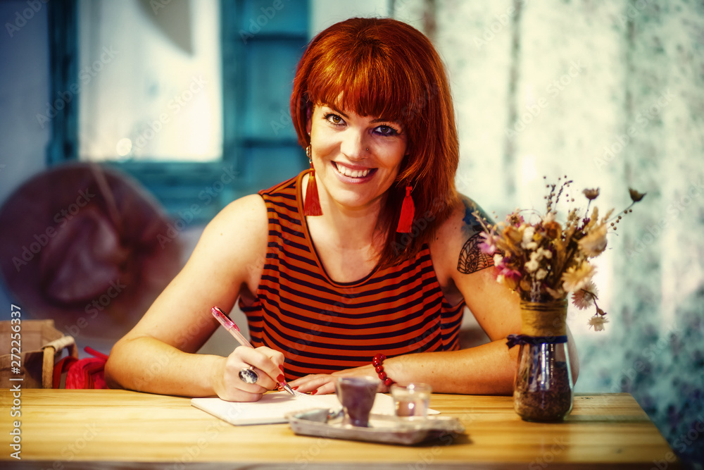 woman is writing in notepad in coofee bar. woman is writing in notepad in coofee bar.