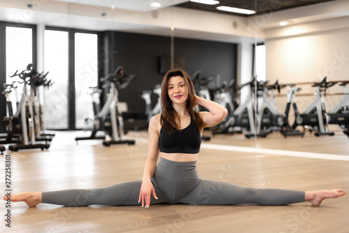 Young sexy woman doing stretching exercises in gym