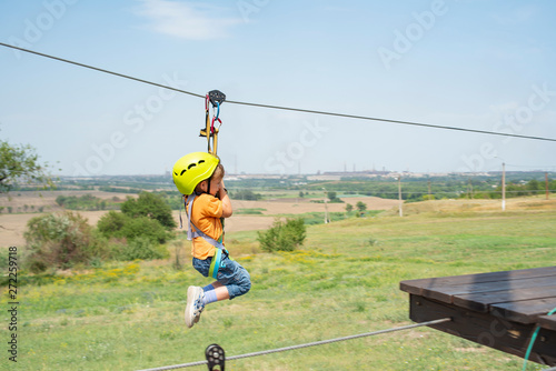 A boy dressed in a protective helmet and insurance, goes down the rope, descends holding a protective cable. © andov