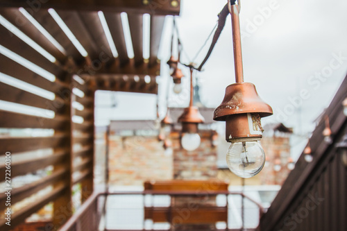 a garland of white light bulbs hangs on the ennobled roof of the house. wooden gazebo on the housetop overlooking the neighboring and sky. penthouse
