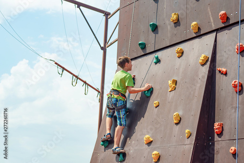Rock climbing on an artificial rise. The boy climbs on the wall in an extreme park.