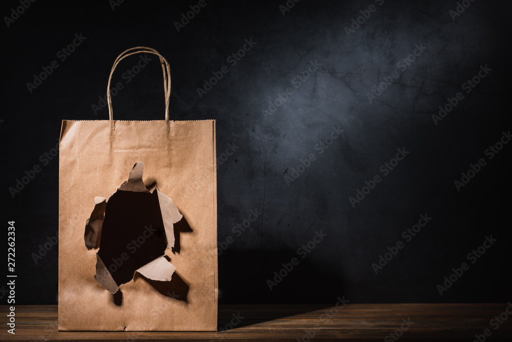 hole ripped craft paper shopping bag on wooden table Stock Photo