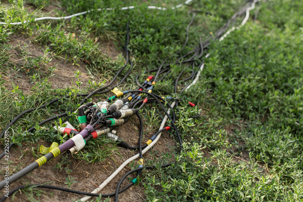 Naklejka premium Connectors for music and microphone for a festive party. Wires with connectors xlr lie on the ground and on the grass