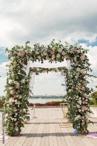 A festive chuppah decorated with fresh beautiful flowers for an outdoor wedding ceremony photo