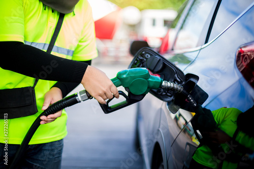 hands refilling the car with fuel at the gas station.