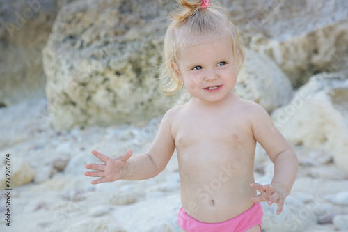 Candid portrait of a cute blonde baby girl enjoying a day at the rocky beach 
