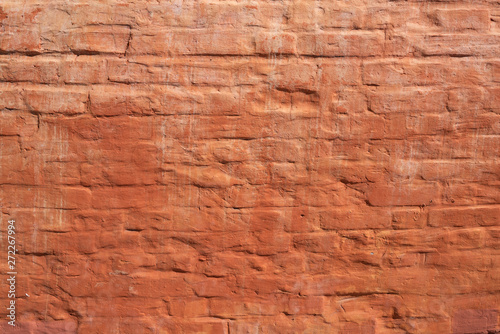 Red brick wall with smooth seams, covered with lime or plaster