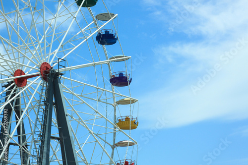 Multicolour ferris wheel on blue sky background. Copy space, street photography.