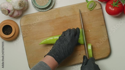 Chopping sweet green pepper on a wooden board