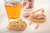 Herbal tea with pharmaceutical chamomile, dry chrysanthemum and hunters on a white table