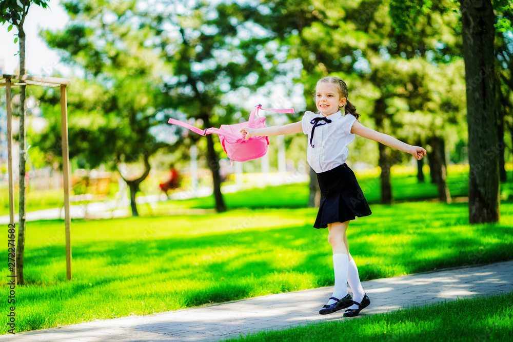 Portrait of happy Caucasian young smiling girl wearing school backpack outside the primary school. schoolgirl, elementary school student runs jumping from school, graduation, summer holidays. Portrait of happy Caucasian young smiling girl wearing school backpack outside the primary school. schoolgirl, elementary school student runs jumping from school, graduation, summer holidays.