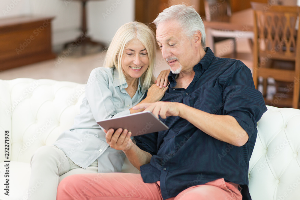 Mature couple using a digital tablet in their apartment Mature couple using a digital tablet in their apartment