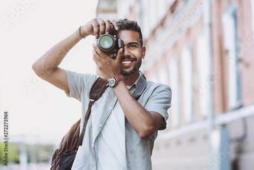 Young man photographer takes photographs with dslr camera in a city. Travel, vacations, professional freelance work and active lifestyle concept photo