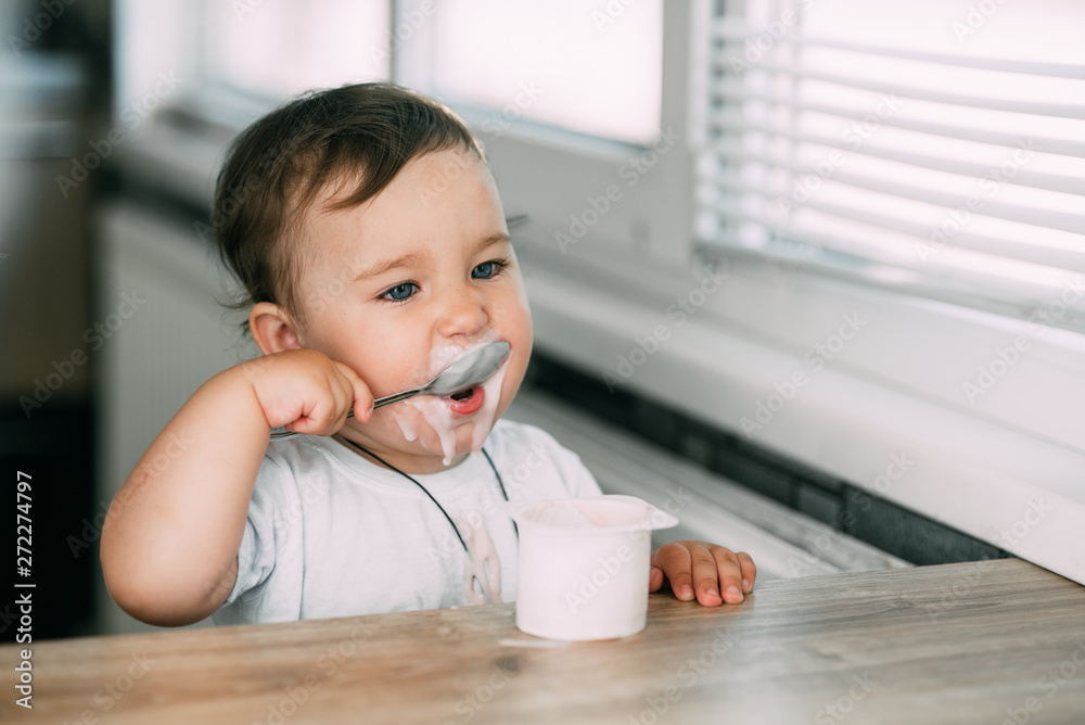 A little charming girl eats yogurt all smeared herself A little charming girl eats yogurt all smeared herself