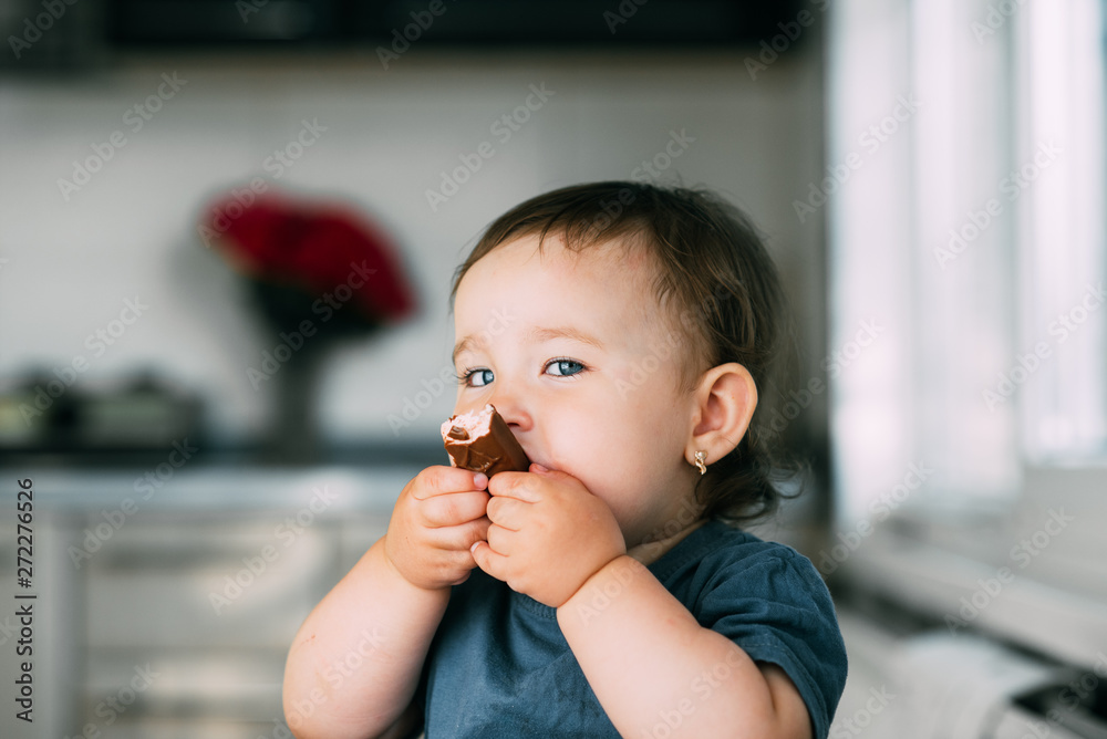 little girl in the afternoon in the kitchen eating a delicious chocolate bar little girl in the afternoon in the kitchen eating a delicious chocolate bar