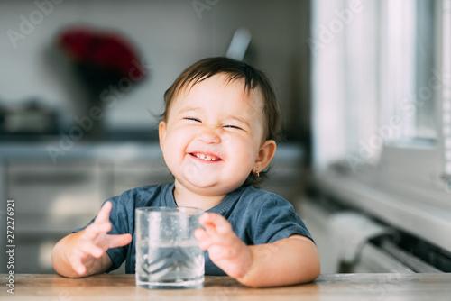 Cute little girl sitting in baby chair and drinking water