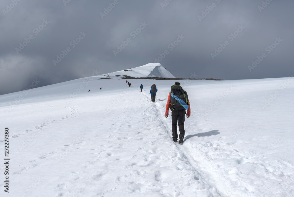 Hikers in approach of Glittertinden mountain summit, climbing trough Glitterbreen glacier.