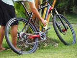 A man washes a mountain bike in the backyard.