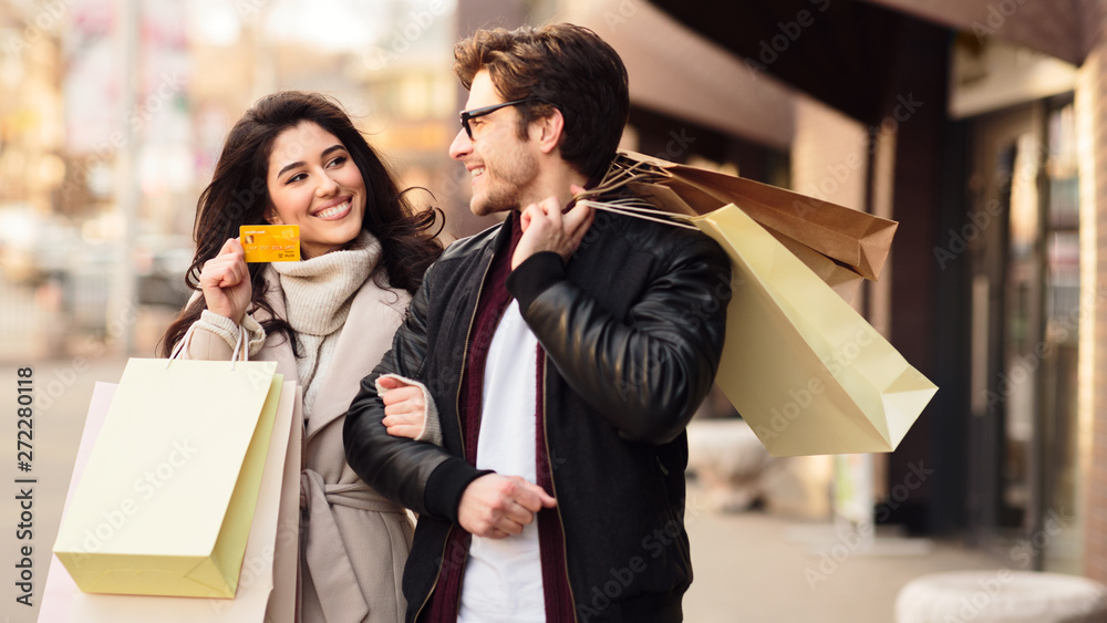 Couple shopping in boutiques, woman showing credit card Couple shopping in boutiques, woman showing credit card