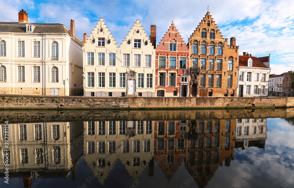 Scenic city view of Bruges canal with beautiful medieval colored houses, bridge and reflections at sunny day.