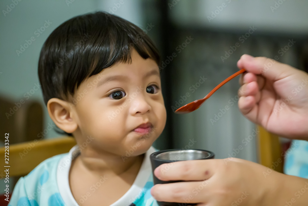 Mother feeding her baby with spoon. Mother giving healthy food to her adorable child at home. woman giving her baby to eat and sitting Mother feeding her baby with spoon. Mother giving healthy food to her adorable child at home. woman giving her baby to eat and sitting