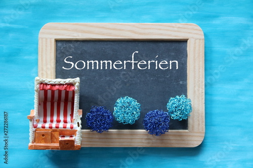 Dekoration Sommerferien mit Schieefertafrl und Strandkorb als Symbol für Strandurlaub photo