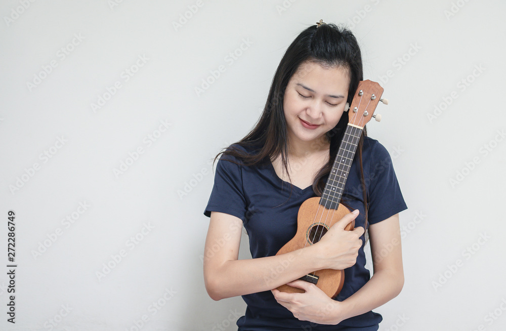 Closeup asian woman with ukulele on white cement wall texture background Closeup asian woman with ukulele on white cement wall texture background