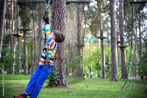smiling boy rides a zip line. happy child on the zip line. The kid passes the rope obstacle course