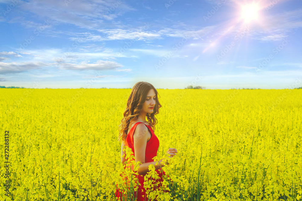 Young beautiful girl in a red dress close up in the middle of yellow field with radish flowers and sunlight.. Young beautiful girl in a red dress close up in the middle of yellow field with radish flowers and sunlight..