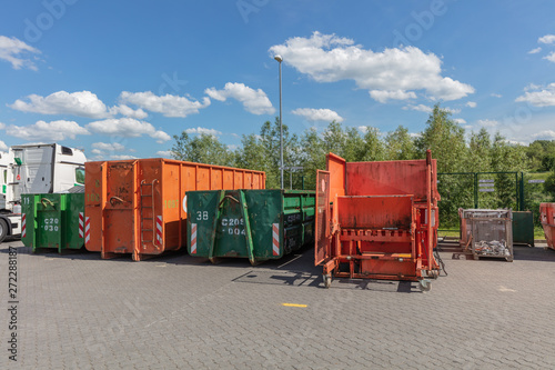 Bild auf Leinwand orange waste compactors are standing on a factory site with other waste containe