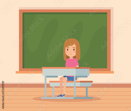 girl child in the classroom with desk and blackboard