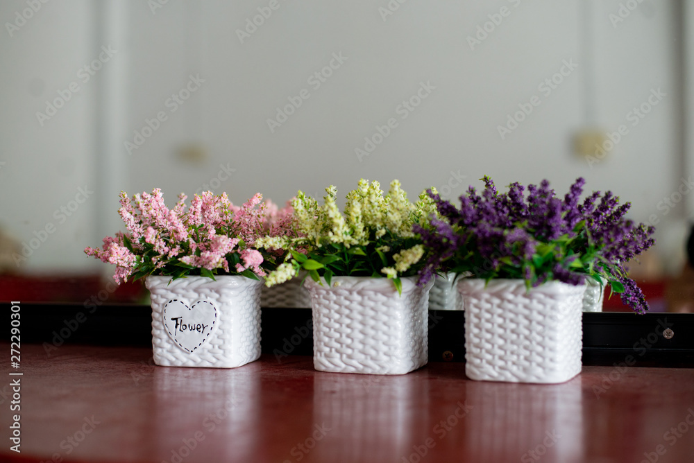 Fototapeta premium A bouquet of flowers in a vase on a wooden table, reflecting with a mirror