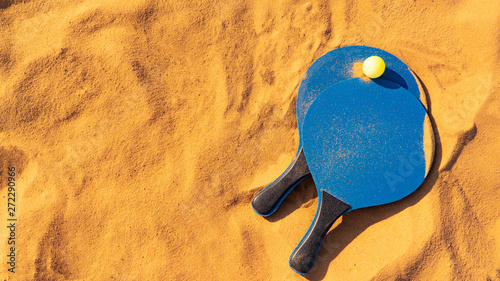 blue rackets and green ball on golden sand beach tennis badminton background