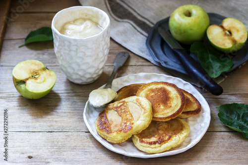Homemade apple fritters with sour cream, coffee and green apples on a wooden background. Rustic style.