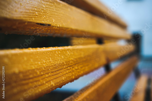 The wooden lacquered bench is covered with drops after rain. photo