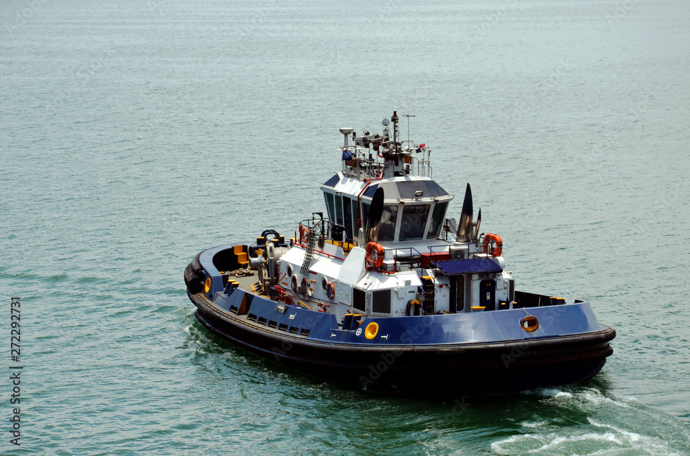 Tugboat assisting to the cargo ship during berthing operation in the port of Cristobal, Panama. 